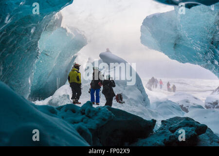 La gente en la entrada de una cueva de hielo, Parque Nacional, el glaciar de Vatnajökull, Islandia