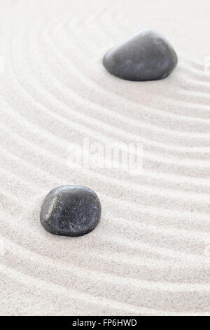 Dos piedras negras en la arena, el spa o concepto zen. Foto de stock