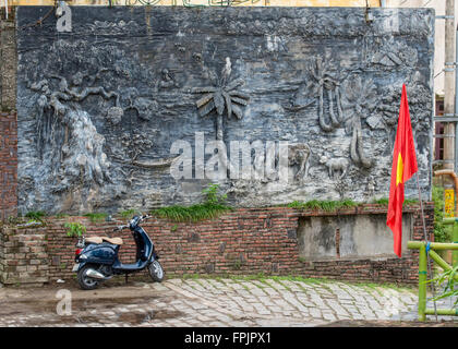 Hoi An, Vietnam, escena callejera con scooter, bandera vietnamita y un mural que muestra una escena campestre y seascape Foto de stock