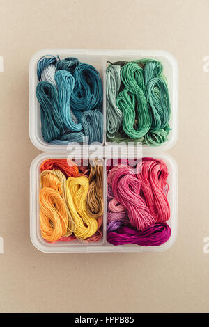 Hilos multicolores, organizada por colores en una caja de plástico Foto de stock