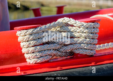 Amarre la cuerda torcida en un barco rojo. Cuerda es blanco, pero un poco sucias y muy bien utilizado.