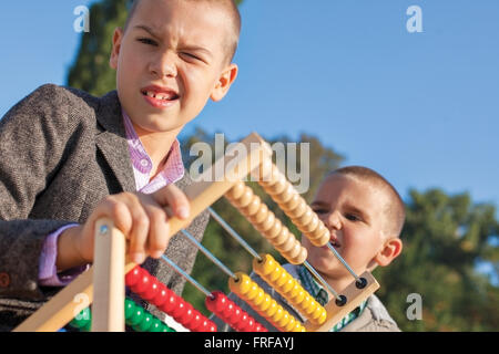 De vuelta a la escuela confunde dos chicos jugando con ábaco de madera en el parque. Uno alrededor de siete, el ather cuatro. Foto de stock