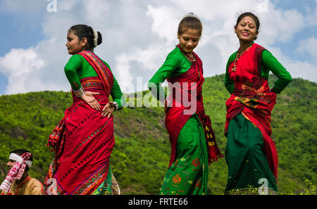 Un grupo de mujeres en saris tradicionales realizan la danza Bihu en el aire abierto en un brillante día de verano. Foto de stock