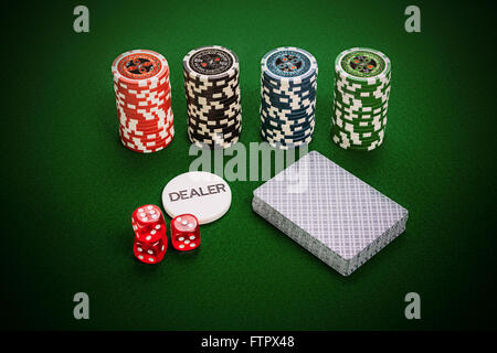 Fichas de Casino, una baraja de cartas, el concesionario chip y rojo dados de casino casino verde acostado en la tabla. Foto de stock