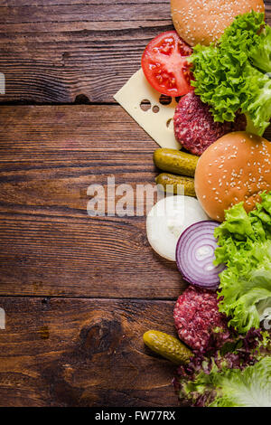 Ingredientes para las hamburguesas sobre la mesa de madera, el borde del fondo con espacio para copiar la receta o texto. Foto de stock