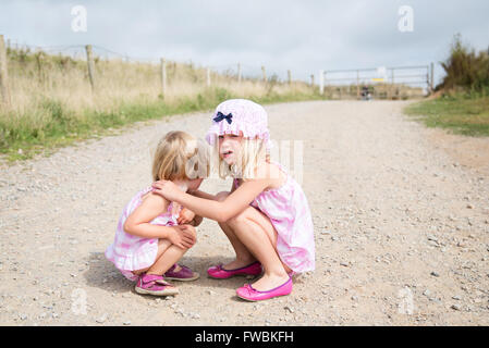 Dos niñas en cuclillas un consolador Foto de stock
