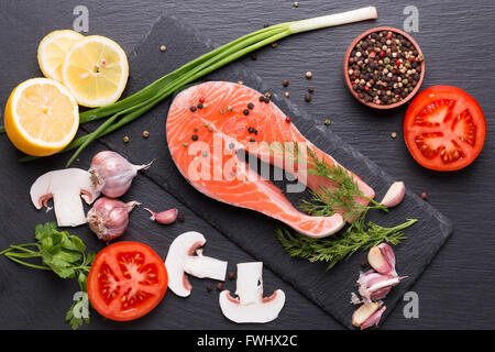 Filete de pescado rojo con especias y verduras en una tabla de pizarra. Foto de stock