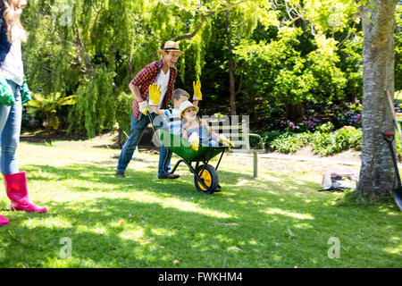 Padre llevar a su hijo e hija en una carretilla de mano Foto de stock