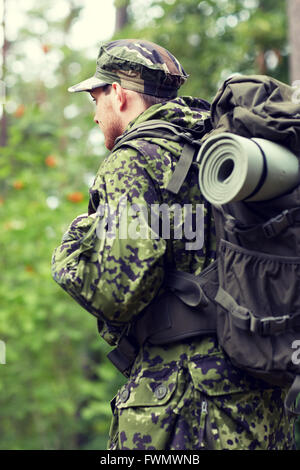 Un joven soldado con uniformes y chaleco táctico trabaja en el bosque y se  prepara para la acción