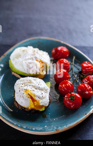 Desayuno, setas con aguacate y huevos escalfados y tomates cherry asado sobre la vid