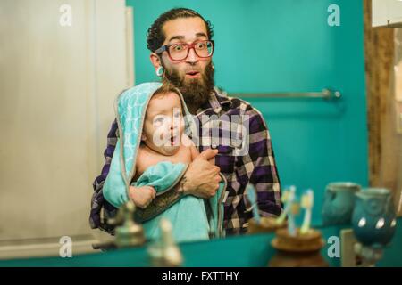 Imagen de espejo de la joven e hijo tirando de caras en el baño. Foto de stock
