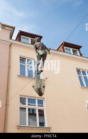 Cuerda floja la escultura de pescador, un caminante equilibrio sobre la cuerda entre dos edificios celebración exterior peces en la red. Foto de stock