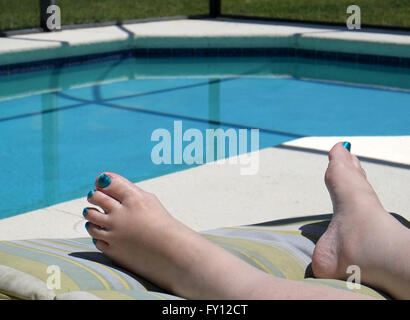 Los pies de una mujer madura, vistiendo el barniz de uñas en sus dedos para que coincida con el color de la piscina. De abril de 2016