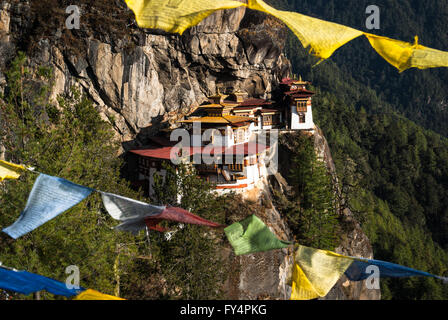 Vista entre banderas de oración a Tiger's Nest (Monasterio de Taktshang), encaramado sobre un acantilado cerca de Paro, Bhután