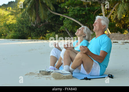 Pareja de ancianos meditar en la playa Foto de stock
