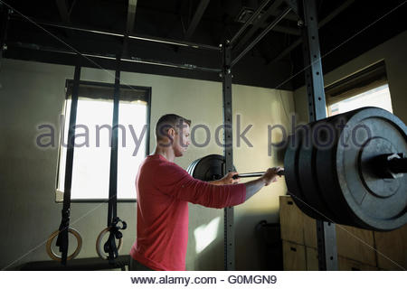 Hombre de pie en cuclillas barbell rack a gimnasio