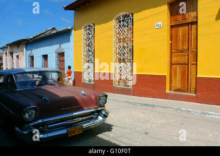 Casas de colores en una escena en la calle. Viejo clásico americano Chevrolet rojo coche estacionado en una calle con el tradicional, en el fondo, Trinidad, Cuba, Las Antillas, América Central