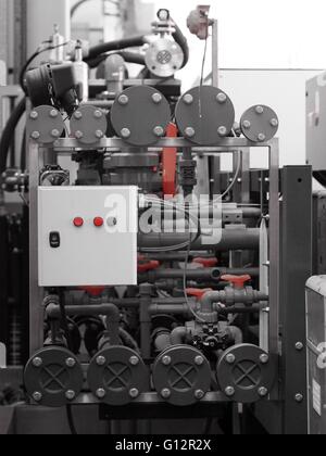 Maquinaria industrial y tubos con cuadro de control e interruptores rojos y válvulas Foto de stock