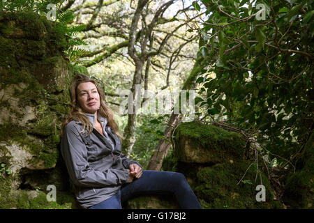 Excursionista hembra sentado en woodland rocas cubiertas de musgo, España
