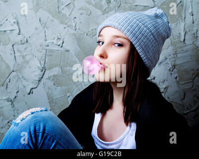 Adolescente con un chicle contra el viejo muro Foto de stock