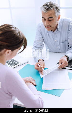 Mujer joven reunión un consultor profesional en su oficina, él es la celebración de un documento y dar explicaciones Foto de stock