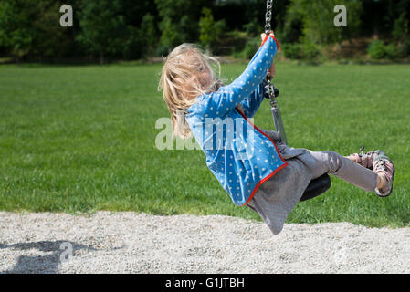 Niño feliz chica rubia (edad 5) se deshace en Flying Fox el equipo para jugar en un playground para niños. Verano Foto de stock