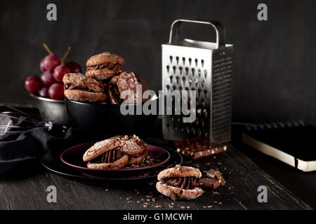 El italiano maroni cookies en el plato y el cuenco con las uvas, tela, portátil en el oscuro fondo antiguo de madera Foto de stock