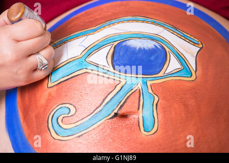 Maquillaje artista crear Ojo de Horus pintando en el vientre de una mujer embarazada Foto de stock