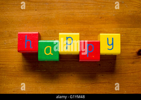 Bloques de madera coloridas la ortografía de la palabra/cartas feliz Foto de stock