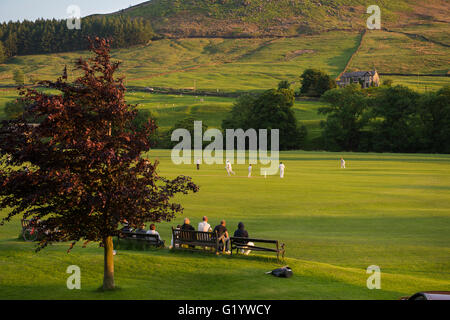 Un idílico entorno rural de los espectadores a sentarse y observar una soleada tarde de verano, partido de cricket - Burnsall, Valles de Yorkshire, Inglaterra. Foto de stock