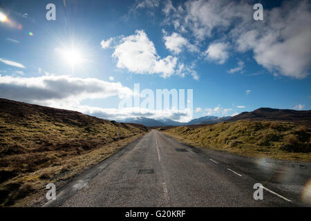Nubes blancas mullidas e interminable camino abierto en la A832 en el extremo noroeste de Escocia, Reino Unido