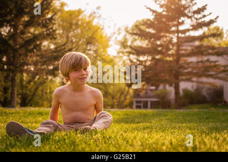 Muchacho sentado en el jardín de hierba