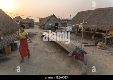 Joven caminando en una aldea típica, con casas y barcos de pescadores, Mandalay, Myanmar, Birmania, Asia Meridional, Asia Foto de stock