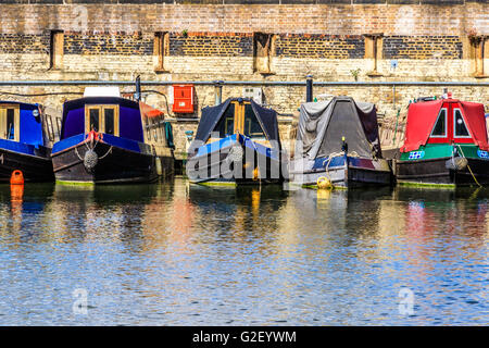 Filas de casas botes y barcos por el estrecho canal de bancos en St Pancras Yacht Basin, parte del Regent's Canal en Londres Foto de stock