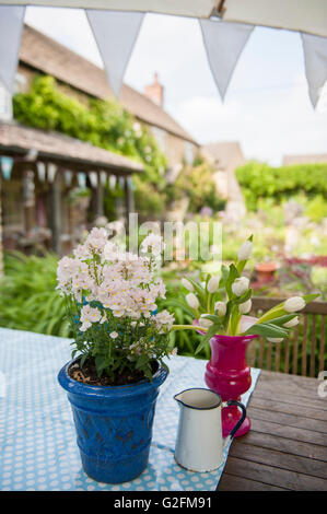 Las macetas sobre una mesa de jardín bajo bunting Foto de stock