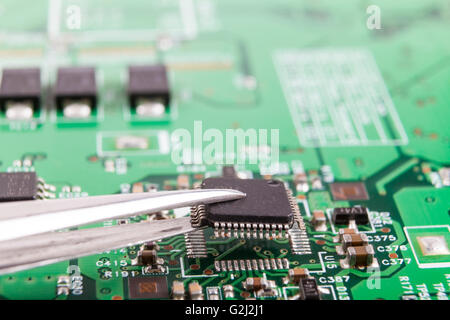 Microchip de montaje en placa de circuito electrónico con pinzas Foto de stock