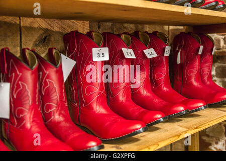 La mujer botas vaqueras rojas para la venta en la tienda de botas