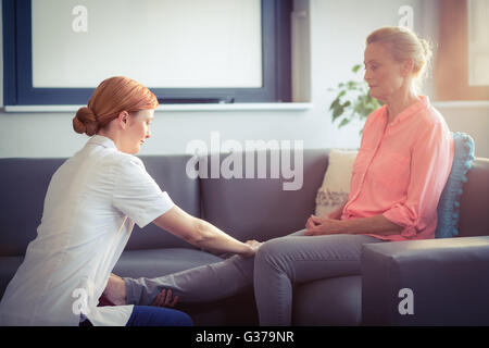 Enfermera dando masaje de la pierna para mujer Foto de stock