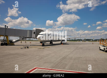 Avión de pasajeros blanco estacionado en la explanada del aeropuerto a la puerta Foto de stock
