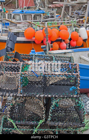 La langosta creels, redes y flotadores a bordo de barcos pesqueros amarrados en el puerto de Cornualles con marea baja. Foto de stock