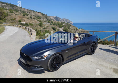 Mujer conduciendo el Ford Mustang convertible de 5 litros V8 con la parte superior abierta.