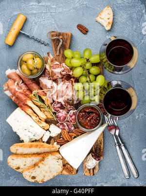 Selección de aperitivos de carne y queso. Prosciutto di Parma, salami, palos de pan, rodajas de pan baguette, aceitunas, tomates secados al sol, gra Foto de stock
