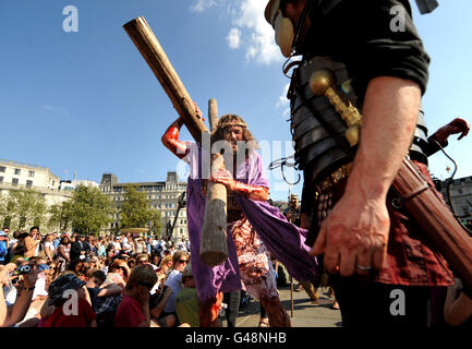 Jesús lleva la cruz durante una actuación al aire libre de la Pasión de Jesús en Trafalgar Square en Londres para marcar el Viernes Santo. Foto de stock