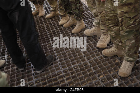Una visión del calzado del primer ministro británico David Cameron (izquierda) mientras se reúne con oficiales del Ejército Nacional afgano durante una visita al campo de entrenamiento de ANA en el campamento Bastion, provincia de Helmand, en el sur de Afganistán. Foto de stock