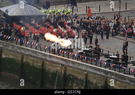 Un Salute Real es disparado desde la orilla norte del río Támesis cerca de Tower Bridge, Londres, mientras el Diamond Jubilee River Pageant pasa. Foto de stock