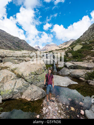 Joven parado en una piscina con una pequeña cascada en las montañas, el río Golo, Parque Natural de Córcega