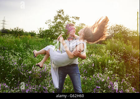 Feliz amor hombre sujetando una mujer en sus brazos en el campo Foto de stock