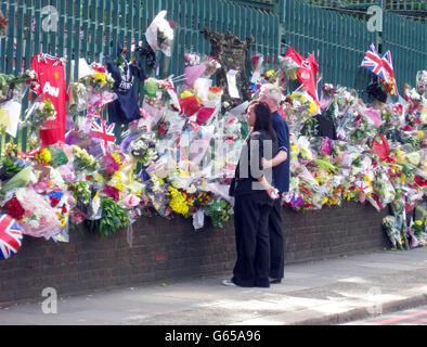 Los miembros de la familia del baterista Lee Rigby miran los tributos florales fuera de Woolwich Barracks mientras visitaban la escena de su asesinato en Woolwich, al sureste de Londres.
