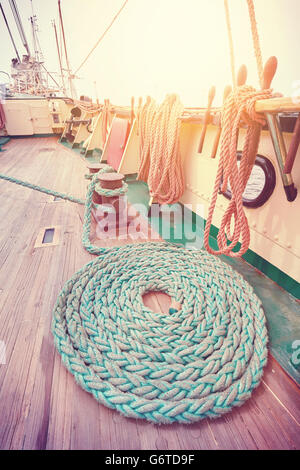 Imagen de ángulo amplio de tonos vintage de amarre la cuerda sobre la cubierta de madera de un velero. Foto de stock