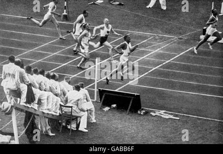 (R-L) Jesse Owens de EE.UU. Rompe la cinta para ganar oro mientras su compañero de equipo Ralph Metcalfe llega a casa para ganar plata, con el holandés Martinus Osendarp reclamando bronce Foto de stock